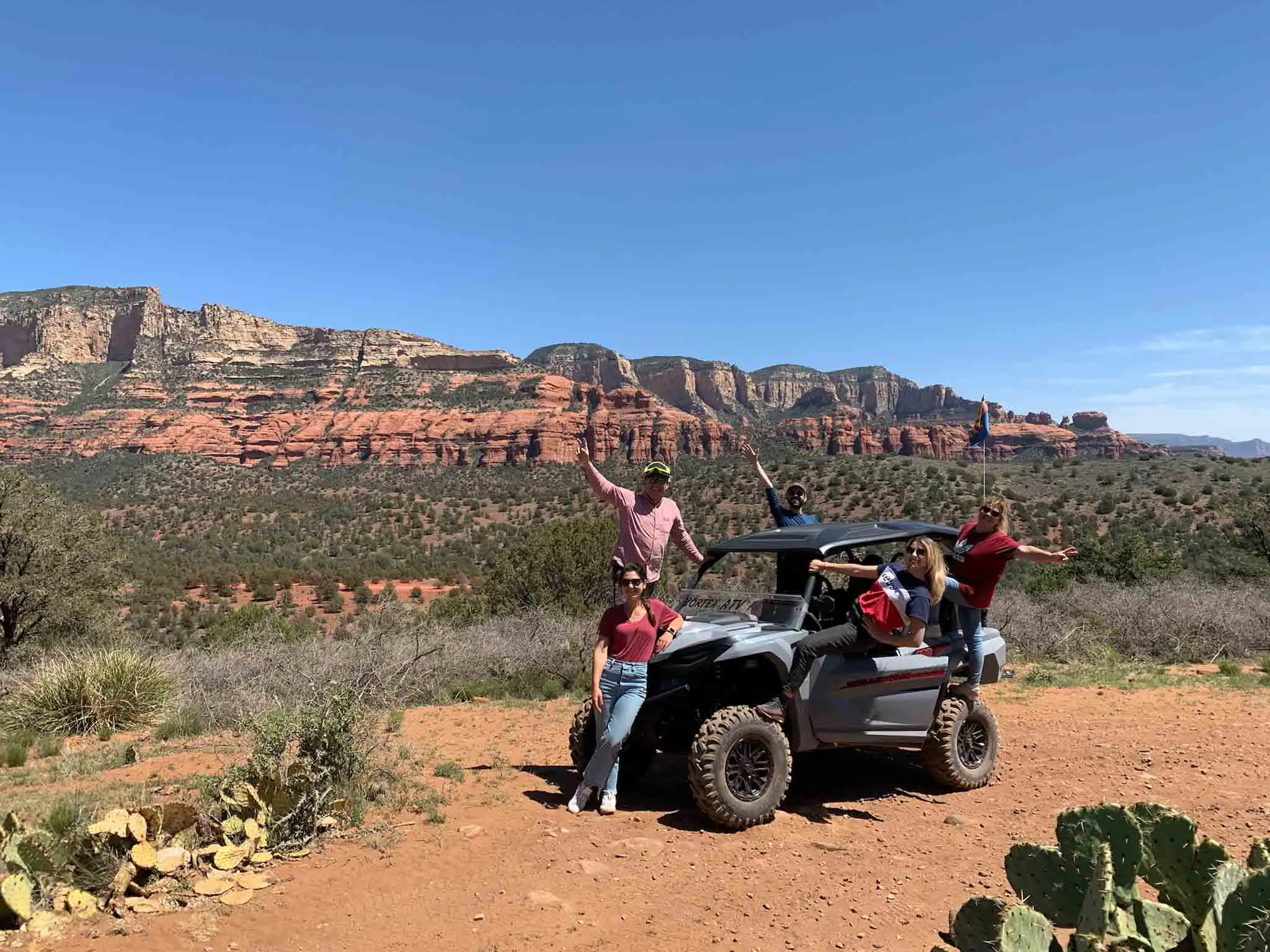 Group of ATV Renters posing for a photo in front of the red rock landscape